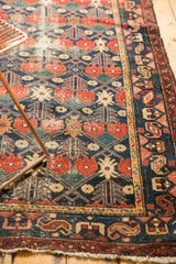 Vintage Baktiari rug corner with traditional red, navy, and beige lattice motifs and tattered fringe.