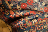 Folded vintage Baktiari rug detail, highlighting navy, cherry red, green floral lattice.