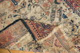Close-up of tattered fringe, worn ivory ground, and geometric border on antique Shirvan rug.