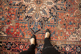 Vintage Heriz carpet's oversized concentric medallion, geometric patterns in brick red and navy blue.