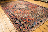 Vintage Heriz carpet corner detail showing brick red, navy, ivory geometric spandrel motifs.