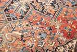 Hand-knotted Heriz rug close-up revealing intricate geometric patterns in brick red, navy, sky blue, and ivory.