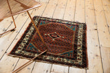 A collector's vintage Persian Engelas rug shown at an angle, displaying its rich ruby rust pile.