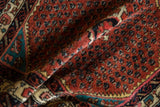 Low pile texture and hand-knotted boteh motifs in ruby red and sapphire blue on a vintage rug.