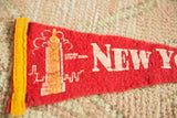 Vintage red felt pennant close-up showing Empire State Building and worn white print.