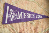 Purple felt pennant with white graphic of woman, sailboat, and Mission text.