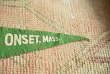 Green felt pennant with white 'ONSET, MASS.' lettering, textured hand-knotted rug background.