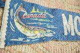 Aged patina on the colorful fish and Canada graphic of a vintage blue felt pennant.