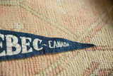 Aged white lettering on the dark blue felt tip of a vintage Canada pennant.
