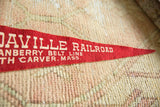 Red felt Edaville Railroad pennant with white lettering, partial view on textured background.
