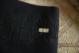 Black felt pennant detail, orange stitched letters, and 