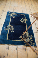 Close-up of an early 20th century Peking rug corner, indigo field, beige floral motif, double border.