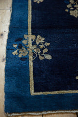 Antique Chinese Peking rug with indigo field, coffee floral spray, double border, and low pile.