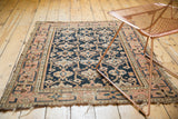 Antique Caucasian rug with dark navy geometric guls, pale dusty blush border, and tattered ends.