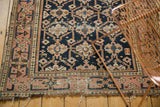 Antique Caucasian rug's tattered end, blush border with meandering vine motif, and visible pile wear.