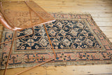 Antique Caucasian rug corner: blush border, meandering vine motif, and tattered fringe.