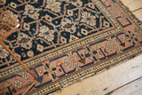 Antique Caucasian rug's dusty blush border with meandering vine motif, showing tattered edge.