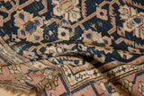 Folded antique Caucasian rug detail, geometric floral gul motifs, and blush meandering border.