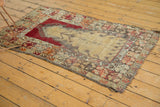 Tattered edges and patterned border of a vintage Turkish Melas rug in red, orange, and beige.