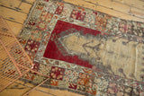 Tattered side edge of vintage Melas rug, showing cherry red, beige, and time-softened pattern.