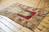 Close-up of a Melas rug corner, revealing beige, cherry red, and tangerine orange geometric border motifs and tattered side.