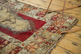 Tattered edge detail of a vintage Melas rug, showing textured red, beige, orange patterns.