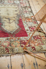 Tattered side, fringe, and red, orange, beige geometric motifs on a vintage Melas rug.