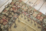 Tattered side and worn pile of a vintage Melas rug corner, revealing beige and faded red patterns.