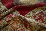 Textured pile of a vintage Melas rug, showing cherry red, sand, and oxidized silver tones.