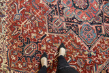 Vintage Heriz carpet: cherry red field, navy and sky blue geometric patterns, even pile wear.
