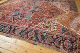 Intricate navy border with serrated leaves and cherry red geometric field of a Vintage Heriz rug.