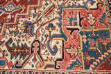 Traditional Heriz rug detail with geometric serrated patterns and softened red, blue pile.