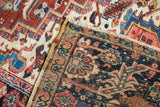 Hand-knotted Heriz rug corner showing polychromatic selvage, fringe, and detailed geometric pattern.