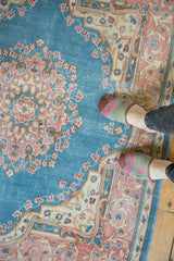 Distressed Kerman rug with a sky blue field, trefoil medallion, and pink floral motifs.