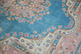 Distressed Kerman rug's low pile, sky blue field with pink florals and ivory trefoil finials.