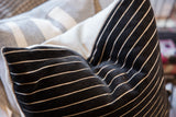 Plush black chenille velvet pillow with fine white wavy stripes and upholstered edge.