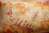 Aged hand-knotted texture of the vintage Turkish rug pillow, with red and yellow patterns.