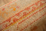 Tight hand-knotted texture of vintage Turkish rug fragment, featuring distressed orange and gold lines.