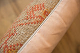 Textured vintage rug pillow with orange pattern, smooth peach backing, and zipper detail.
