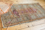 Distressed Oushak runner showing plum field, bright pink flowers, and muted geometric borders.