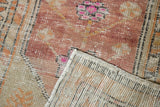 Distressed vintage Oushak rug showing plum and pink floral pile, wear, and hand-knotted reverse.