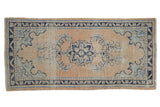 Distressed hand-knotted Oushak runner with pale apricot field, navy floral medallion, visible wear.