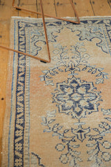 Distressed pale apricot Oushak rug runner showing navy blue geometric border and field motifs.