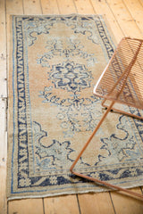 Distressed Oushak runner showing faded navy floral motifs, border, and apricot field.