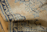 Texture detail of distressed Oushak runner, pale apricot field with navy motifs and visible foundation.