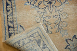 Distressed Oushak runner corner, showcasing worn pile with pale apricot and navy blue patterns.