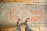 Distressed Oushak runner with tangerine, silver, beige palmettes, stepped contour, and prominent wear.
