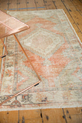 Distressed Oushak rug runner's worn surface with tangerine orange, silver, and beige tones.