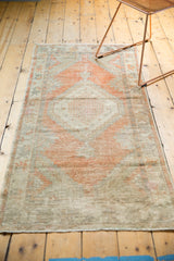 Distressed vintage Oushak runner end, highlighting textural wear and soft tangerine tones.