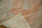 Distressed tangerine, silver, and beige Oushak rug with visible hand-knotted foundation.